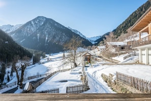 A snow-covered mountain landscape with a wooden structure and buildings in the foreground.