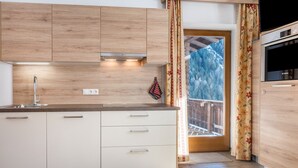 Et moderne køkken med træskabe, indbygget ovn og udsigt til en balkon.