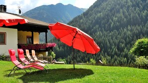 Una casa amb un paraigua vermell, una tanca de fusta i una muntanya de fons.