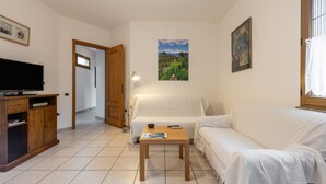 A room with a television, a sofa, a table, a lamp, and a picture on the wall. - Apartment Casa Colonia 1 with Sea View, Shared BBQ and Wi-Fi (Sant'Anna Arresi)