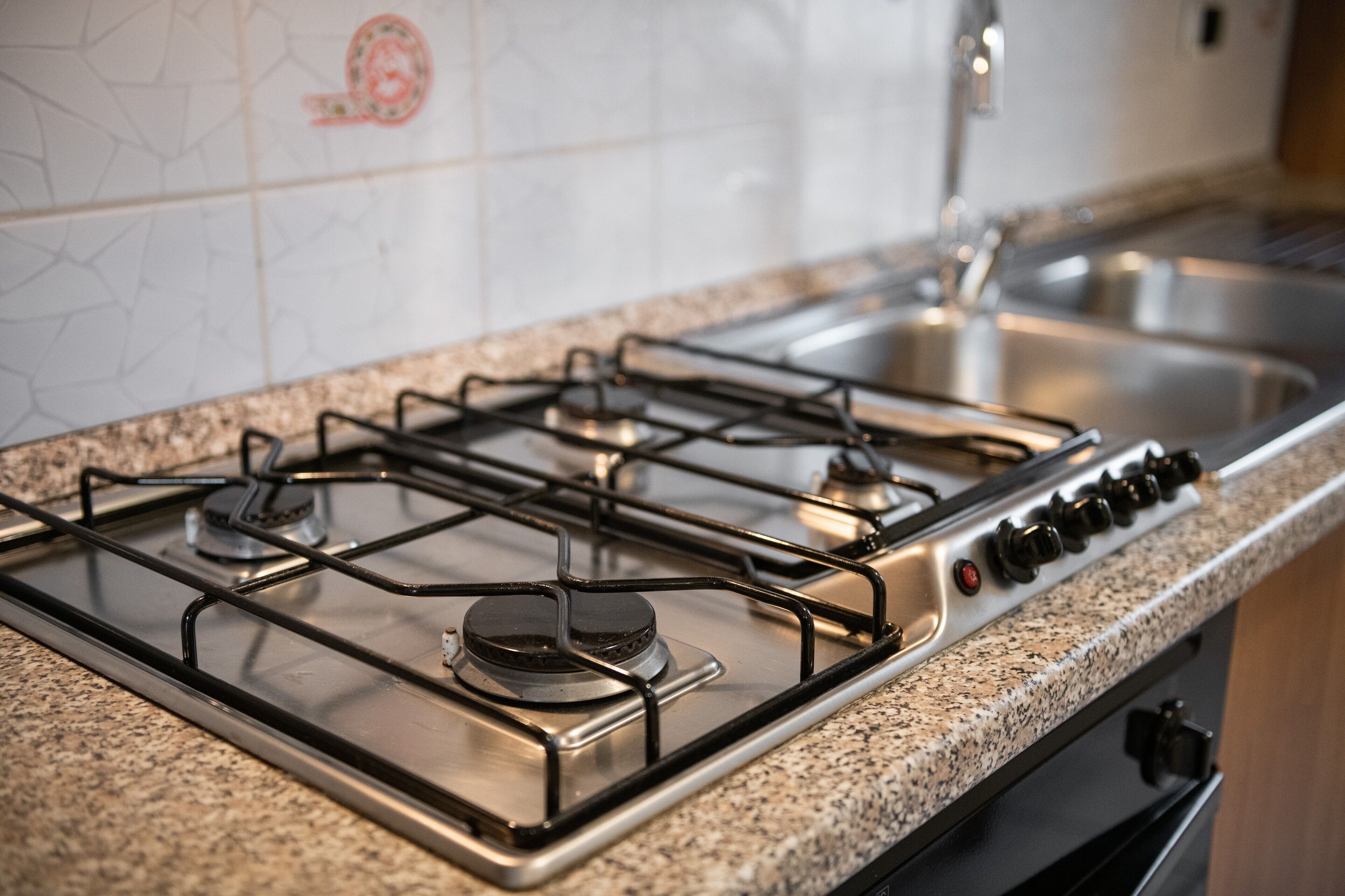 A kitchen with a gas stove, stainless steel sink, and granite countertop.