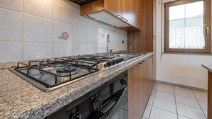 A kitchen with a gas stove, oven, and stainless steel sink. - Apartment Casa Colonia 1 with Sea View, Shared BBQ and Wi-Fi (Sant'Anna Arresi)