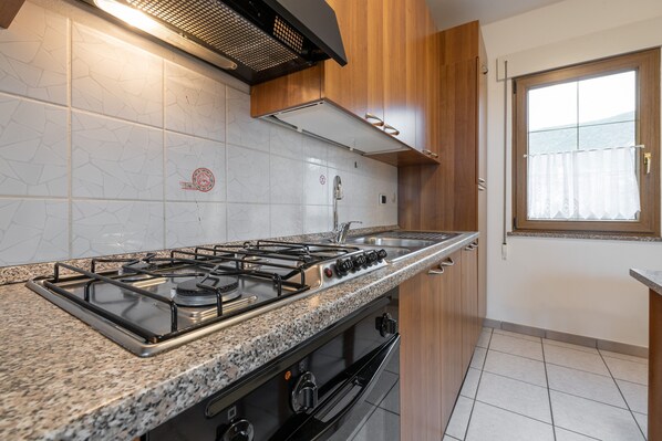 A kitchen with a gas stove, oven, and stainless steel sink.