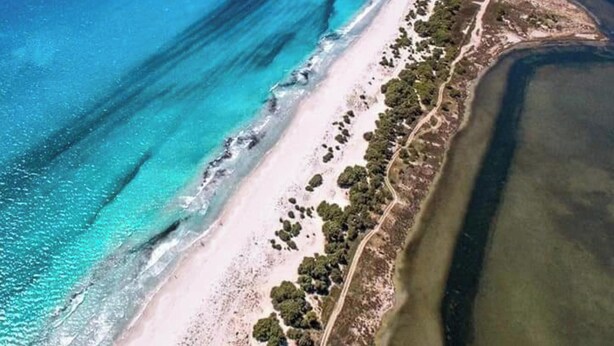 An aerial view of a coastal area with a sandy beach, a road running parallel to the shore, and a small island in the distance. - Apartment Casa Colonia 1 with Sea View, Shared BBQ and Wi-Fi (Sant'Anna Arresi)