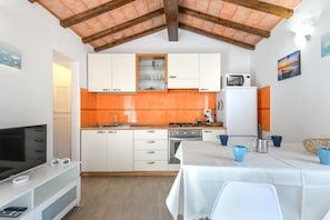Une cuisine compacte avec des meubles blancs, un four à micro-ondes et une table dressée pour le repas.