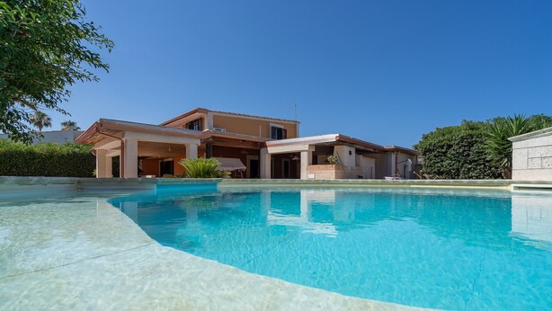 Ein Wohnhaus mit Swimmingpool, überdachter Terrasse und gepflegtem Garten.