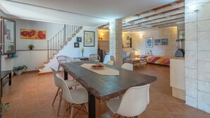 Ein geräumiger Essbereich mit Holztisch und -stühlen, einer Treppe und einer Küchenzeile mit Steinwänden und modernen Geräten.