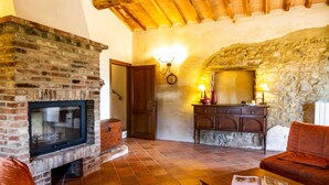 Un salon chaleureux avec une cheminée en briques, un mur en pierre, un plafond en bois et un canapé confortable.