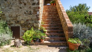 Un bâtiment en pierre avec un escalier en briques menant à une entrée abritée.