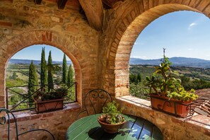 A stone balcony with arched openings, potted plants, and a table with chairs. - Agriturismo "Gli Archi" with Pool, Wi-Fi, and Garden (Civitella Marittima)