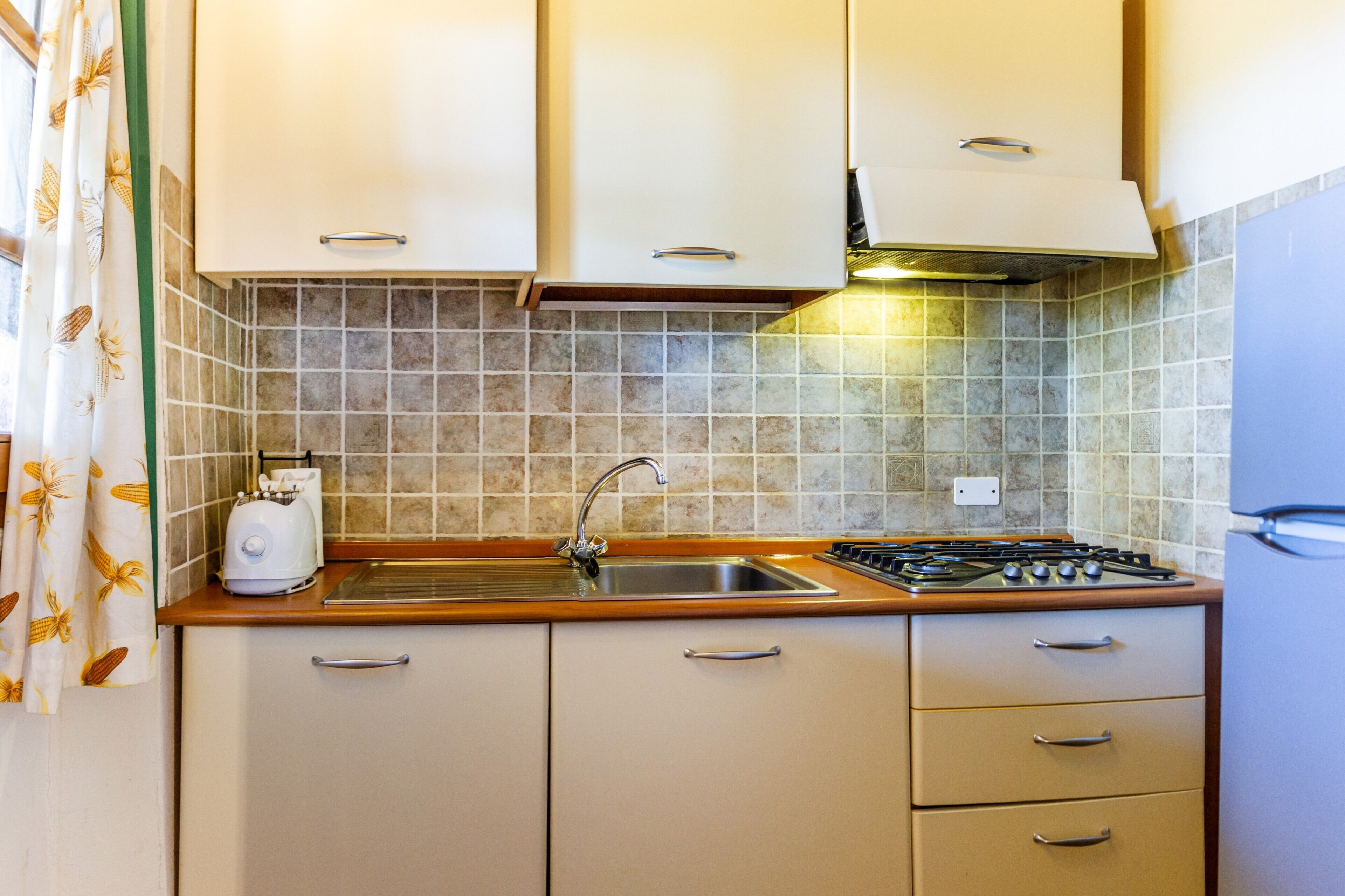 A kitchen with a sink, stove, and cabinets.