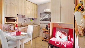 Une cuisine compacte équipée d’un four à micro-ondes, d’une bouilloire et d’une petite table à manger avec des chaises.