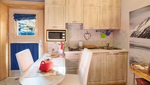 Une cuisine compacte dotée de meubles en bois, d’un four à micro-ondes, d’un évier et d’un coin repas avec une table et des chaises.