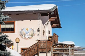 A building with a snow-covered roof, a wooden staircase, and a mural with a mountain scene.