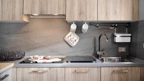 Eine moderne Küche mit Holzschränken, einer Edelstahl-Spüle und einer schwarzen Arbeitsplatte.