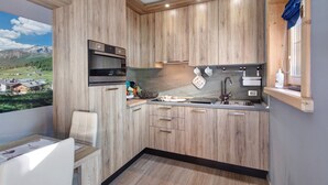 Eine moderne Küche mit Holzausstattung, einem eingebauten Backofen und einem Fenster mit Blick auf eine gebirgige Landschaft.