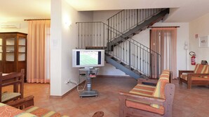 Ein Wohnzimmer mit Fernseher, Holzmöbeln, einer Treppe und einem Feuerlöscher.