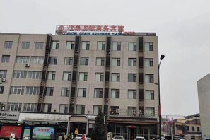 A multi-story building with a commercial ground floor, featuring a variety of storefronts and a prominent sign above the entrance.