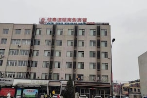 A multi-story building with a commercial ground floor, featuring a variety of storefronts and a prominent sign above the entrance.