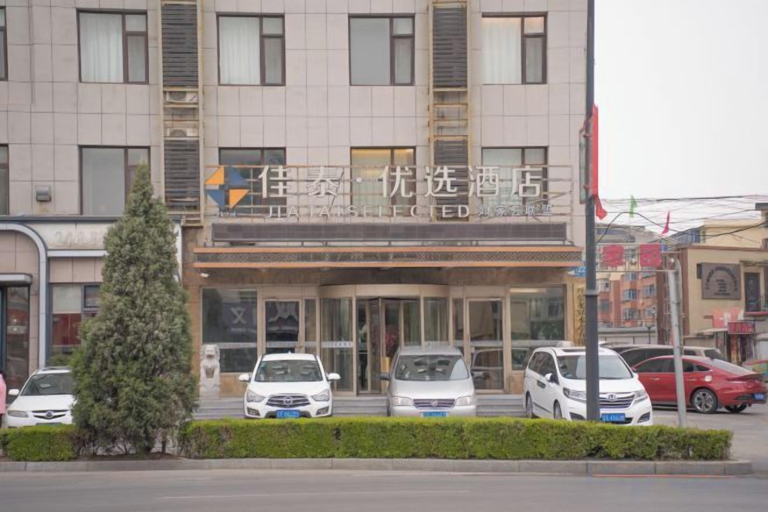 A hotel with a modern facade, multiple cars parked in front, and a clear entrance.