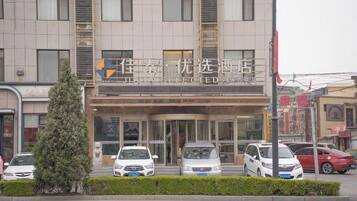 A hotel with a modern facade, multiple cars parked in front, and a clear entrance.