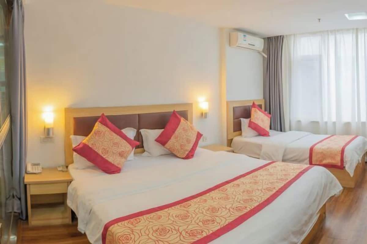 A hotel room with two beds, each with a headboard, bedside tables, and lamps.