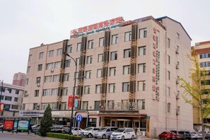A multi-story hotel with a flat facade, multiple windows, and a visible entrance. - Jiatai Chain Hotel Dandonghuanghai Market Store (Donggang)