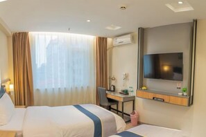 Habitación de hotel con dos camas, un escritorio, un televisor y un equipo de aire acondicionado.