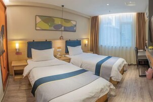Habitación de hotel con dos camas, un escritorio y un ventanal grande con cortinas.