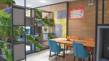 A meeting room with a wooden table, blue chairs, and a plant wall.
