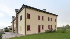 Un bâtiment à deux étages, doté d’une façade beige, de nombreuses fenêtres avec volets et d’une cheminée en briques.