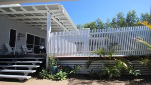 A covered outdoor area with a pool, white deck, and lounge chairs. - Sandy Toes Beach House (HORSESHOE BAY)