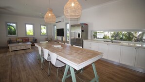 A modern kitchen with a large island, white cabinetry, and a view of the outdoors. - Sandy Toes Beach House (HORSESHOE BAY)
