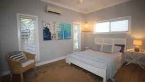 A bedroom with a bed, a chair, and artwork on the wall. - Sandy Toes Beach House (HORSESHOE BAY)
