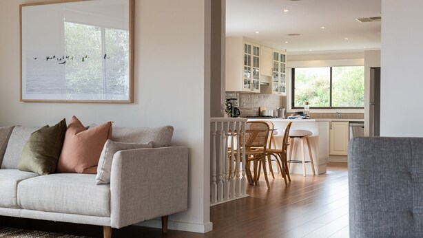 A modern living room with a sofa, a dining area with chairs, and a kitchen with cabinets and a window. - Pet Friendly - Brooklyn Beach Abode Walk to the beach (Safety Beach)
