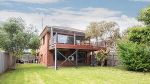 A two-story house with a balcony, a fenced backyard, and a wooden deck. - Pet Friendly - Brooklyn Beach Abode Walk to the beach (Safety Beach)