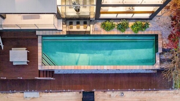 Ein modernes Haus mit Pool auf dem Dach, einer Holzterrasse und Blick auf das Wasser.
