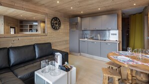 Una cocina moderna con gabinetes grises y electrodomésticos de acero inoxidable, techo de madera y un comedor con mesa y sillas de madera.