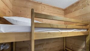 Una cama literera con ropa de cama blanca en una habitación de madera.