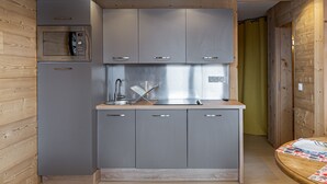 Una cocina compacta con armarios grises, horno empotrado y un lavamanos.