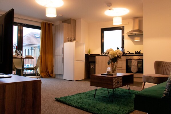 Un espacio habitable compacto con kitchenette, comedor y zona de estar.