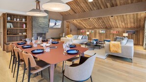 Un vaste espace de vie comprenant une table à manger pour six personnes, un canapé et un téléviseur fixé au mur.