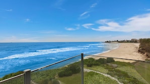 Blick auf einen Strand vom Balkon mit Geländer, das Meer und ein Sandstrand.