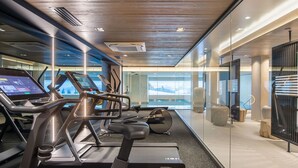 A modern gym with treadmills, stationary bikes, and a rowing machine. - Luxury 3-bedroom apartment in Megève with pool and gym (Megève)