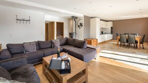 A modern living room with a sectional sofa, a coffee table, and a dining area with a table and chairs. - Spacious apartment 6 pers, terrace sauna close to slopes (Val Thorens)