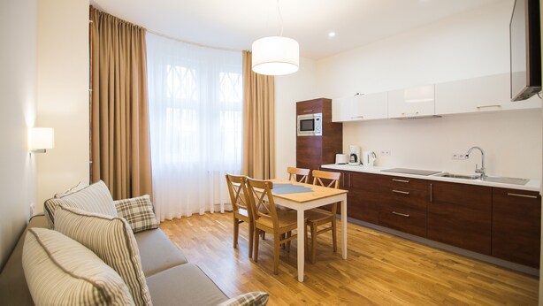 A modern kitchen with wooden cabinets, a dining table, and a built-in microwave. - Apartamenty Swinoujscie - Rubin I (Swinoujscie)