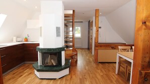 A modern kitchen with a central island, wooden cabinets, and a built-in fireplace. - Apartamenty Swinoujscie - Rubin I (Swinoujscie)