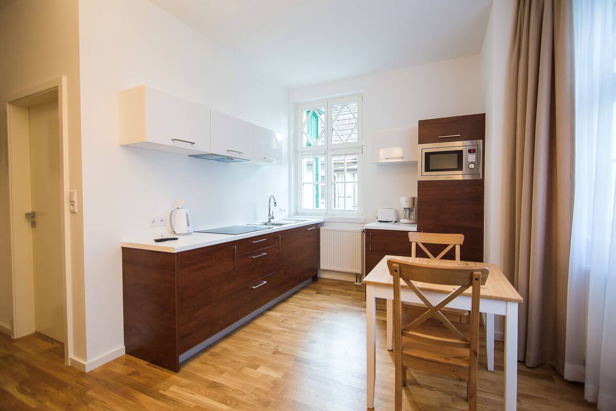 Eine moderne Küche mit Holzausstattung, einer weißen Arbeitsplatte und einer eingebauten Mikrowelle.