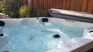 A hot tub with clear water, surrounded by a wooden fence and greenery. - Tesla EV Charger Solar heated Pool & Hot Tub Near UC Davis, Med Center, Airport (West Sacramento)