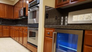 A kitchen with wooden cabinets, stainless steel appliances, and a granite countertop. - Tesla EV Charger Solar heated Pool & Hot Tub Near UC Davis, Med Center, Airport (West Sacramento)
